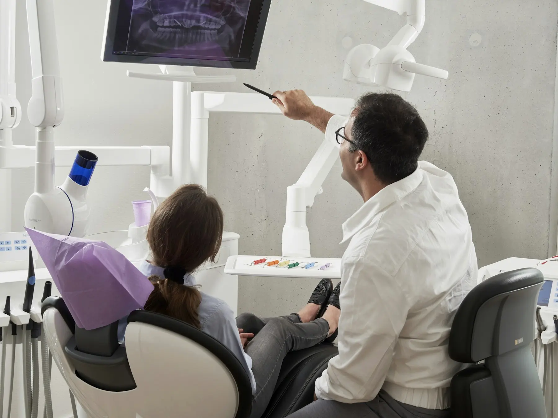 Dentista mostrando imagens de diagnóstico em um monitor para a paciente